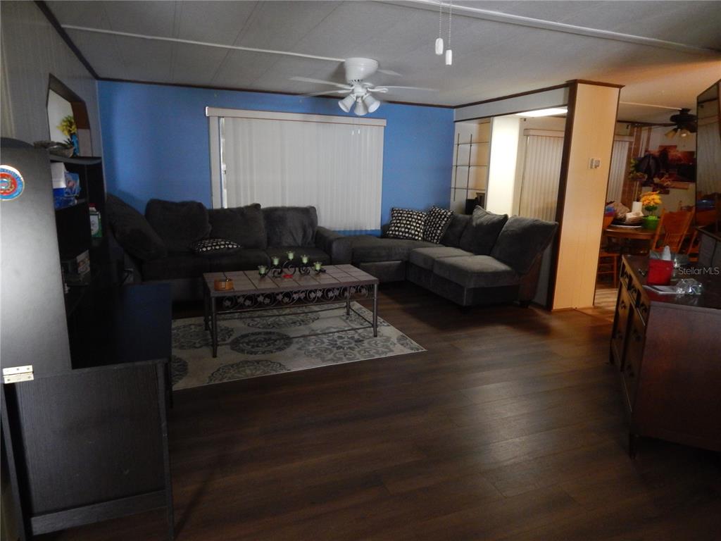A living room features dark wood flooring, a blue accent wall, and a sectional sofa — 6710 36TH AVENUE E UNIT 34, PALMETTO, FL