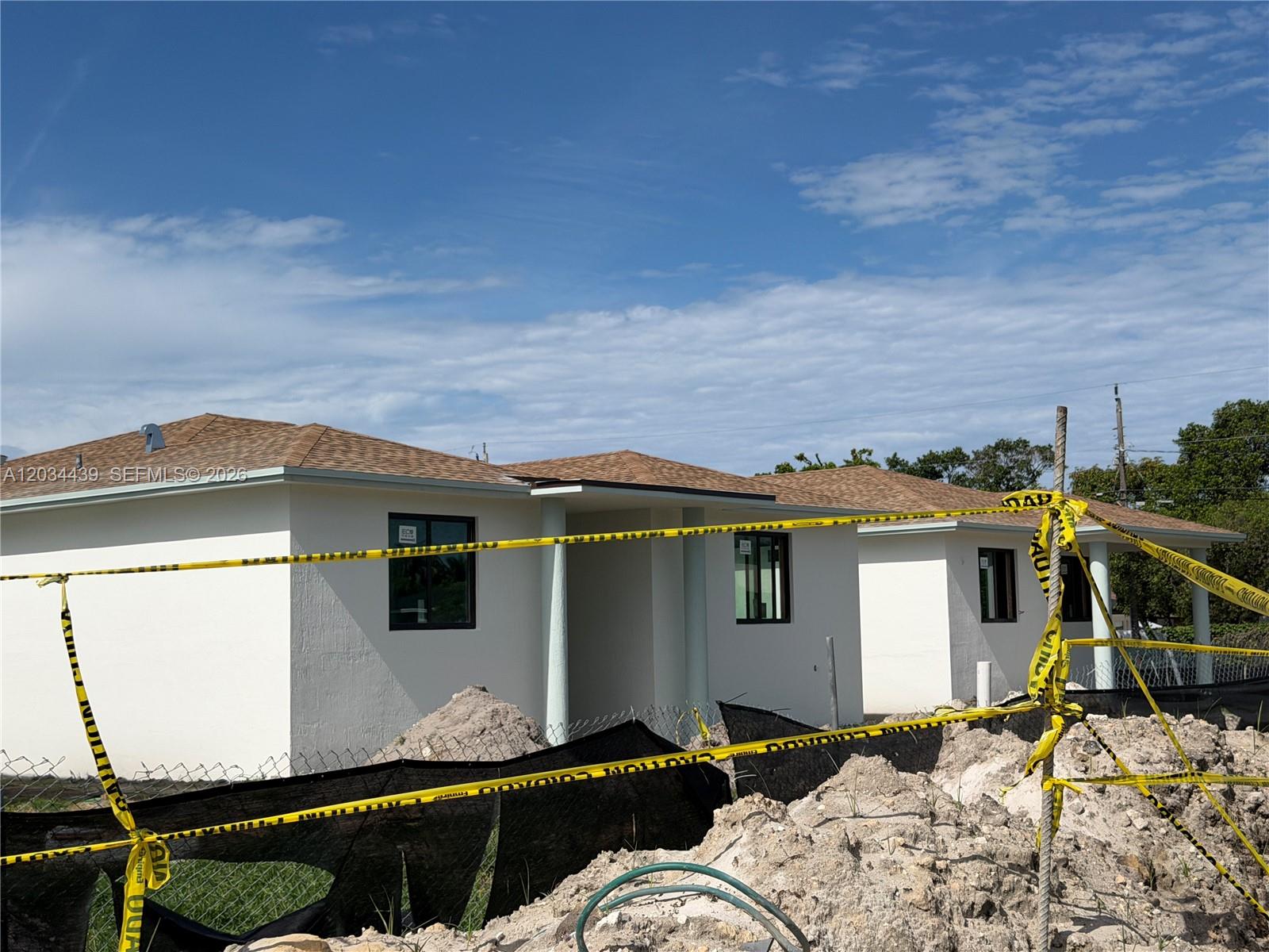 A newly constructed white house with a brown shingled roof sits behind yellow caution tape — 344 NW 11th St, Pompano Beach FL 33060, POMPANO BEACH, FL