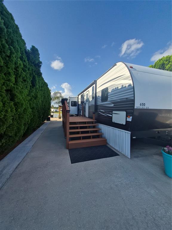 A travel trailer with a wooden deck and stairs sits on a concrete driveway — 650 CENTER CREST BOULEVARD, DAVENPORT, FL