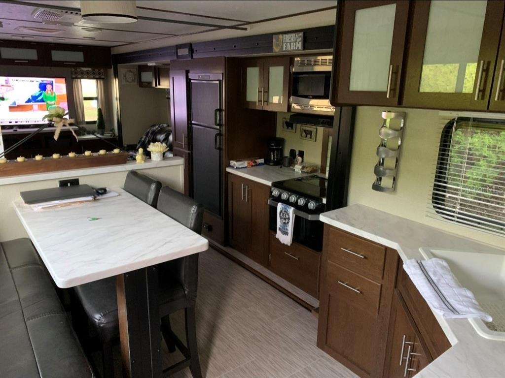 A kitchen and dining area in an RV featuring dark wood cabinets and marble-look countertops — 650 CENTER CREST BOULEVARD, DAVENPORT, FL