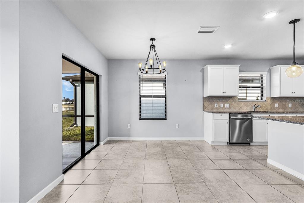 A dining area with tile floors, a chandelier, and a sliding door to the patio — 16033 BEACHBERRY DRIVE, NORTH FORT MYERS, FL