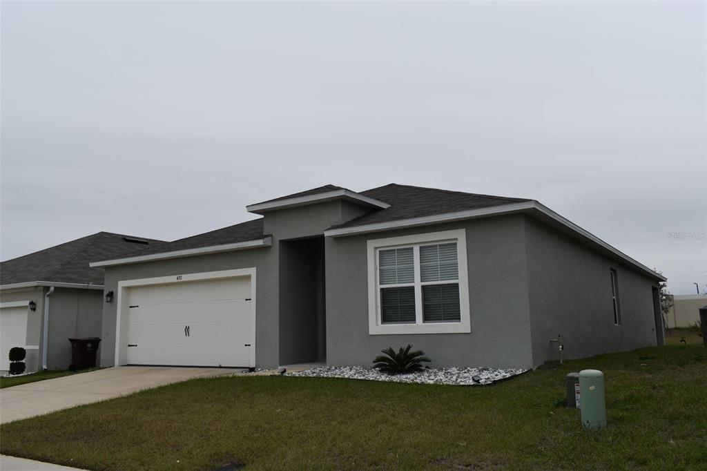 A gray, single-story suburban house with a white garage door and a front lawn — 476 BOARDWALK AVENUE, HAINES CITY, FL