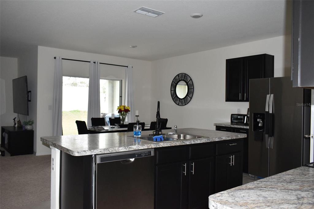 A kitchen island with a sink and dishwasher faces a dining area and living room — 476 BOARDWALK AVENUE, HAINES CITY, FL