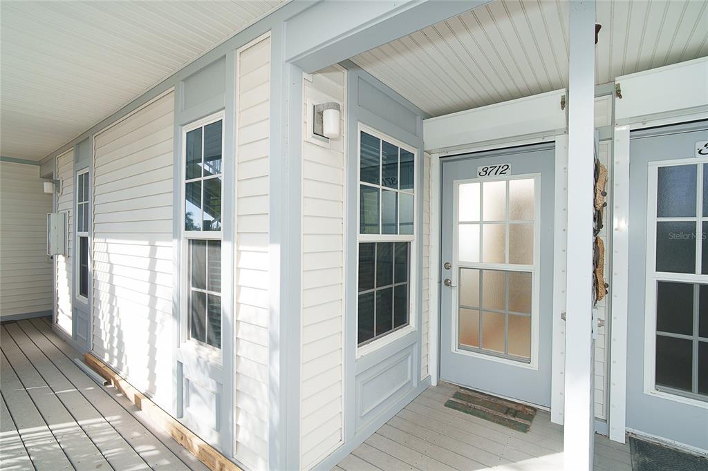 A covered porch with light blue trim, white siding, and two glass-paneled entry doors — 7438 PALM ISLAND DRIVE UNIT 3712, PLACIDA, FL