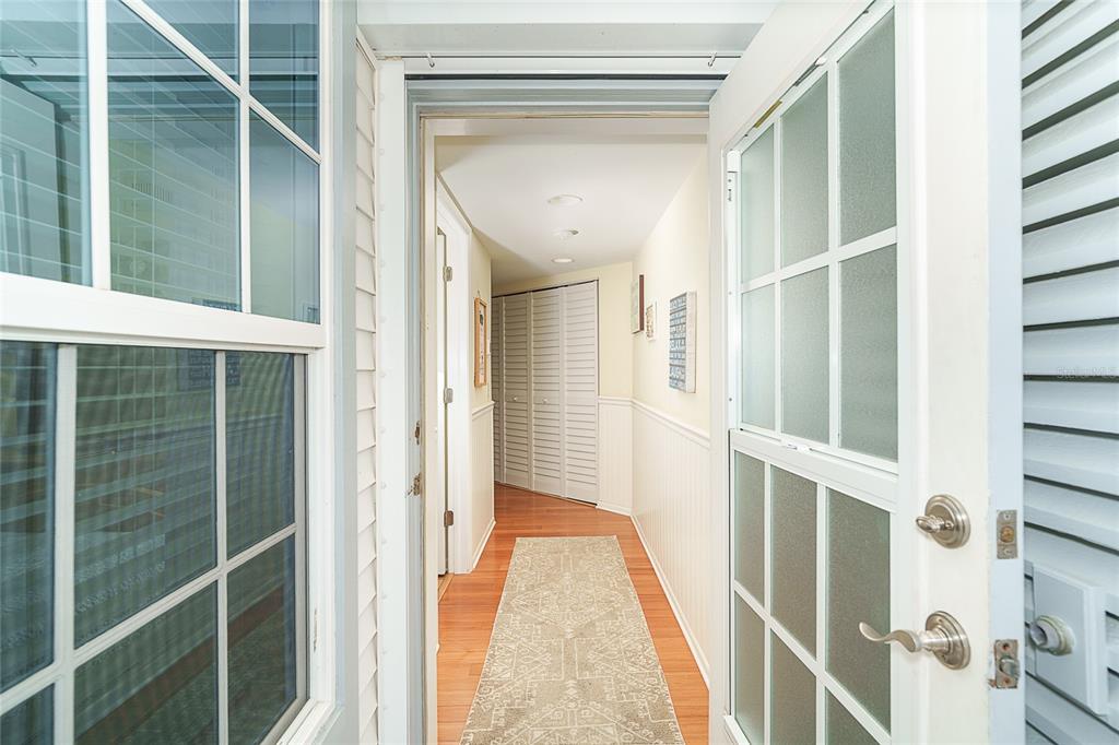 A view through an open door into a hallway with hardwood floors and louvered closet doors — 7438 PALM ISLAND DRIVE UNIT 3712, PLACIDA, FL