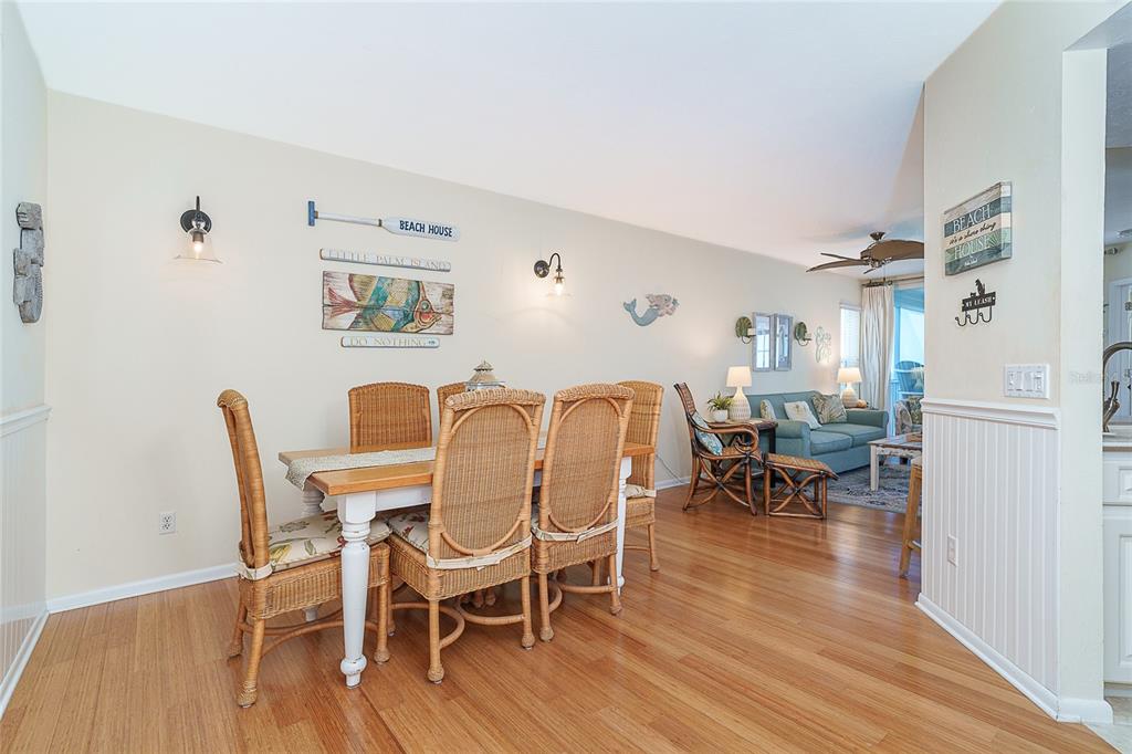 A dining area with wicker chairs and a wooden table opens into a living room — 7438 PALM ISLAND DRIVE UNIT 3712, PLACIDA, FL