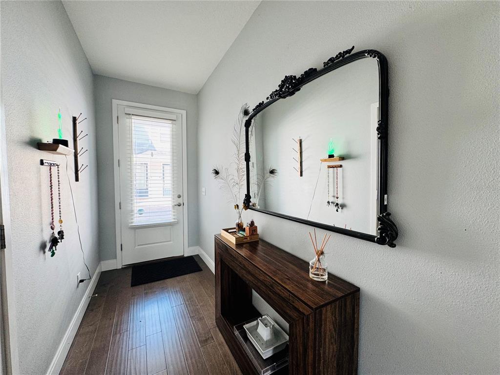 A modern entryway features a dark wood console table, a large ornate mirror, and hardwood floors — 6617 S MANHATTAN AVENUE UNIT 5, TAMPA, FL