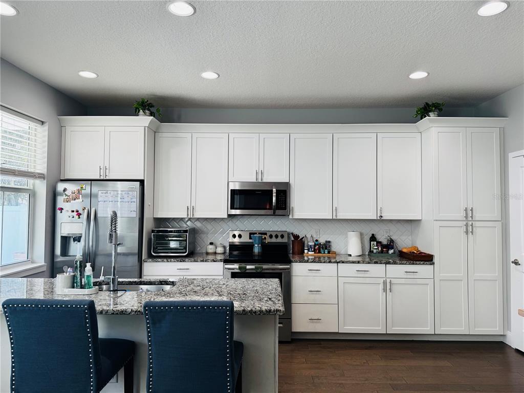 A kitchen features white cabinets, granite countertops, stainless steel appliances, and a blue-seated island — 6617 S MANHATTAN AVENUE UNIT 5, TAMPA, FL
