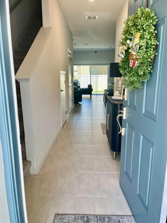 A view from an open blue front door into a tiled hallway with stairs — 2561 PENGUIN BOULEVARD, DAVENPORT, FL