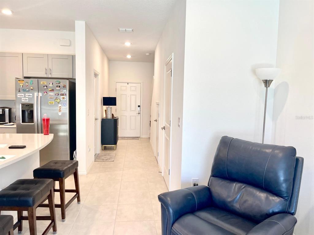 A view of a kitchen island, a hallway leading to an entryway, and a blue armchair — 2561 PENGUIN BOULEVARD, DAVENPORT, FL