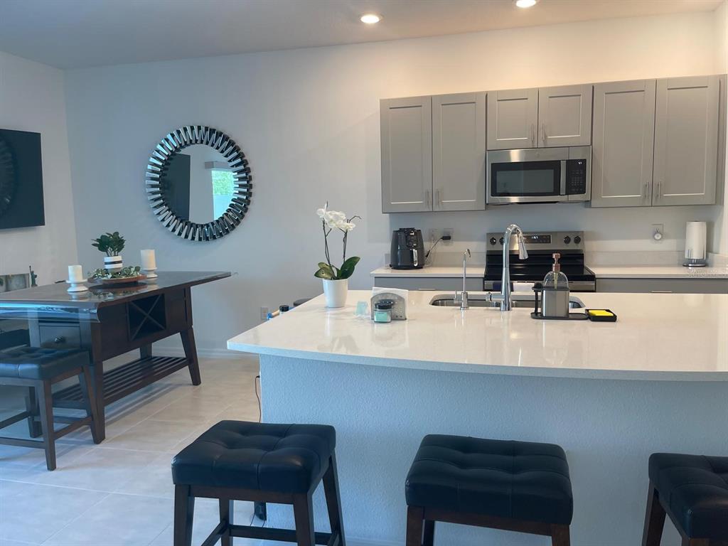 A kitchen features gray cabinets, a white quartz island, and an adjacent dining area — 2561 PENGUIN BOULEVARD, DAVENPORT, FL