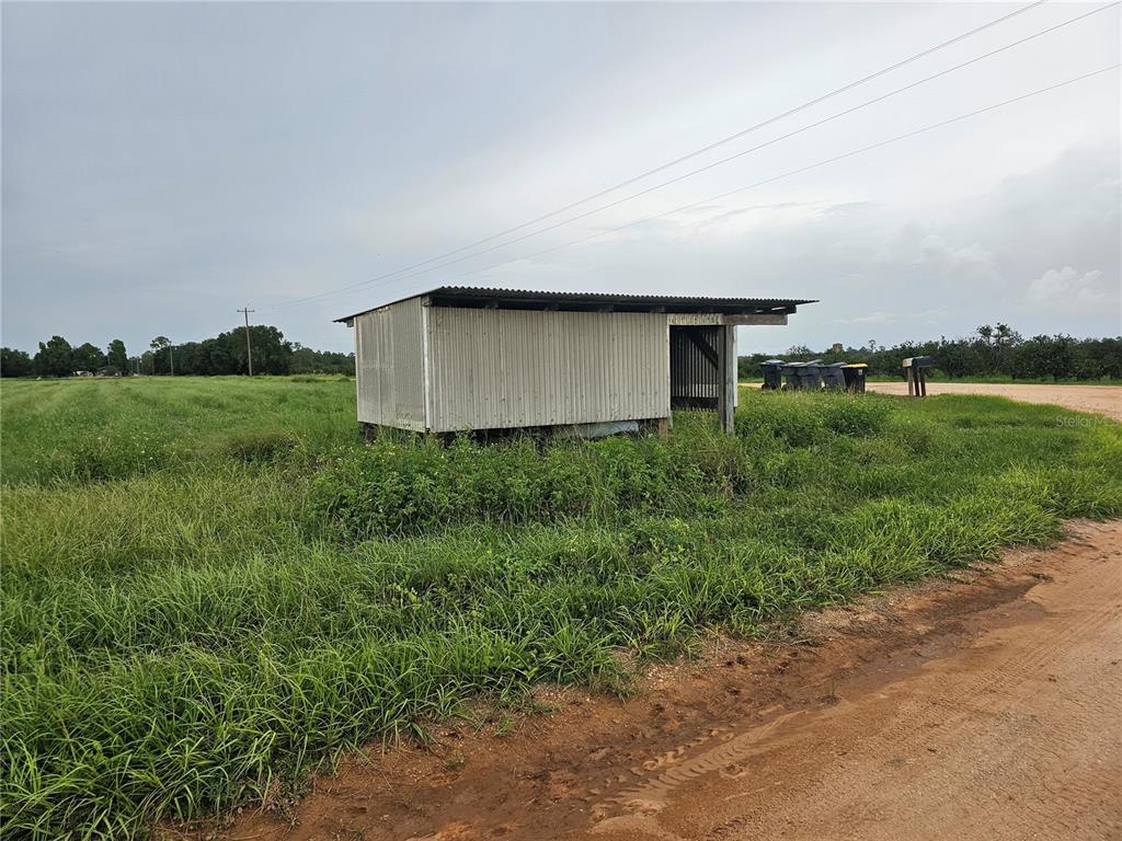 A small, corrugated metal shed sits in a grassy field next to a dirt road — 837 CAMPBELL ROAD, FORT MEADE, FL
