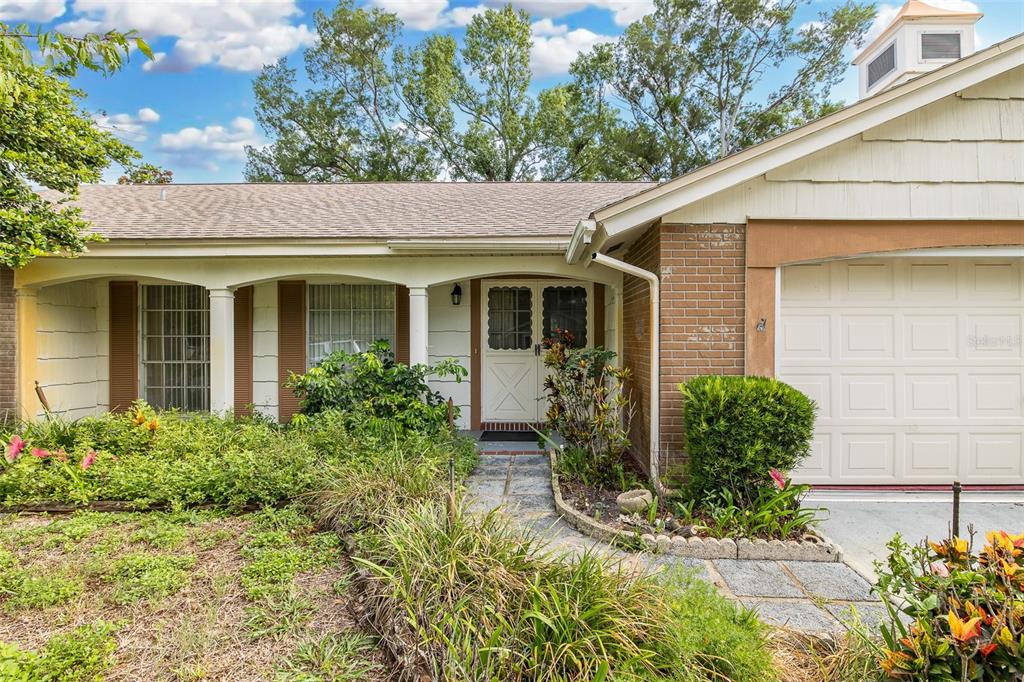 A single-story brick and siding house with a front porch, garage, and landscaped yard — 8315 CAVALRY DRIVE, HUDSON, FL