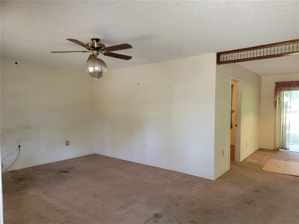 An empty room features beige carpet, a ceiling fan with a disco ball light, and walls — 2240 GABARONE BOULEVARD, AUBURNDALE, FL