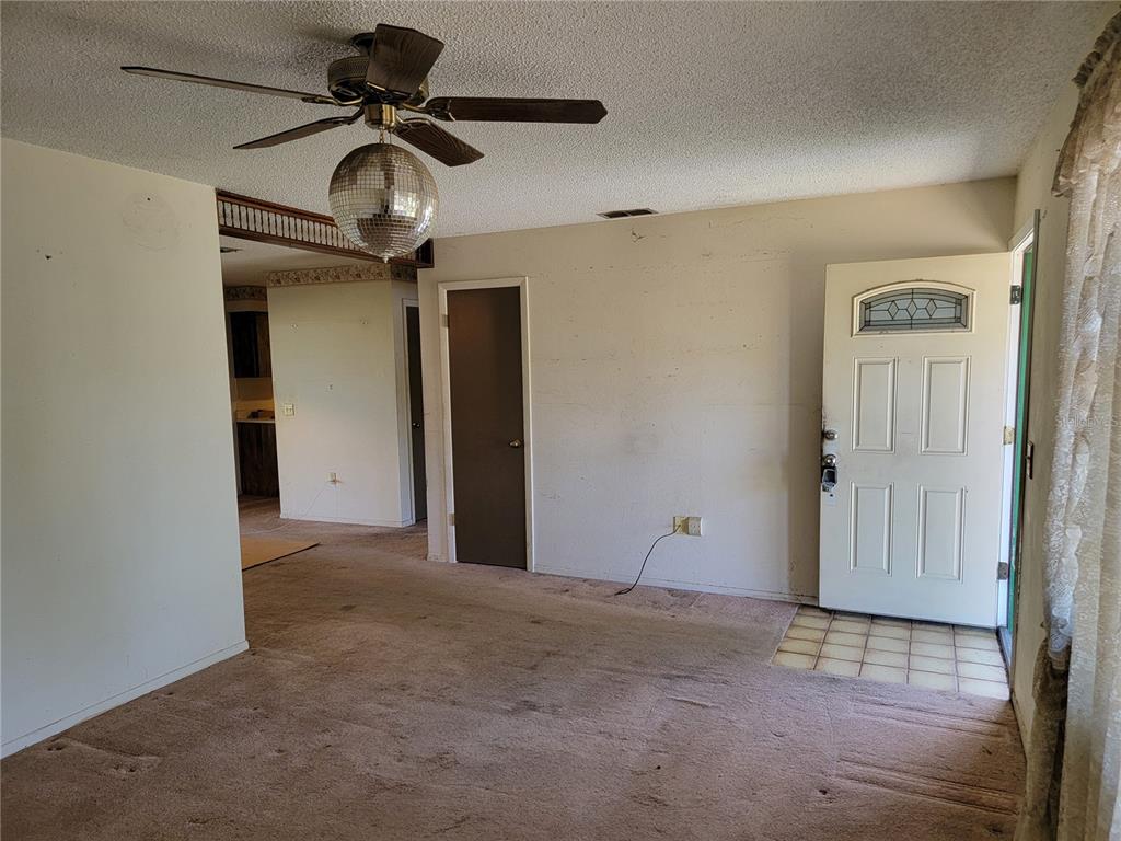 A living room with beige carpet, a ceiling fan with a disco ball, and an entryway — 2240 GABARONE BOULEVARD, AUBURNDALE, FL