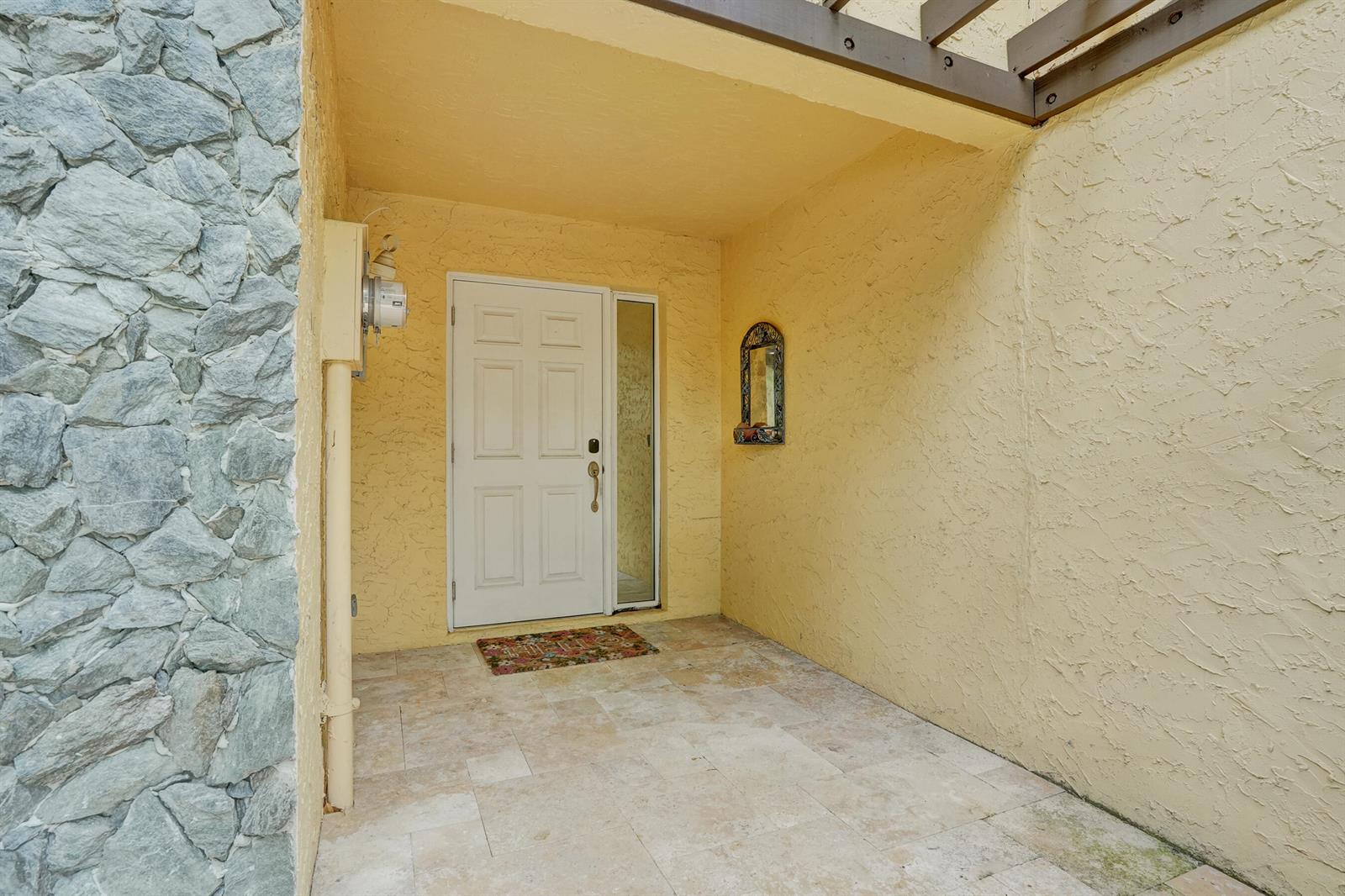 A front entryway features a white door, stone siding, yellow stucco walls, and tiled flooring — 1122 NW 79th Drive, Plantation FL 33322, PLANTATION, FL