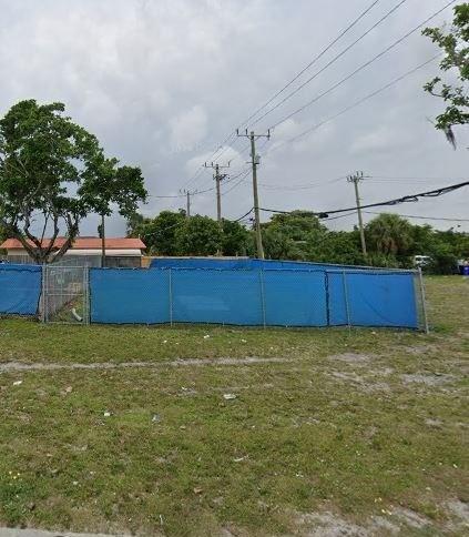 A fenced-in vacant lot with a blue privacy screen and utility poles in the background — NW 27th Avenue, Pompano Beach FL 33069, POMPANO BEACH, FL