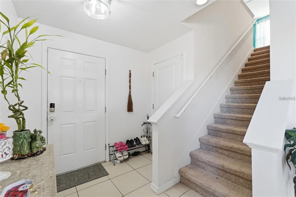 An entryway features a white front door, a shoe rack, and carpeted stairs leading upward — 7811 DAVIE RAY DRIVE, ZEPHYRHILLS, FL