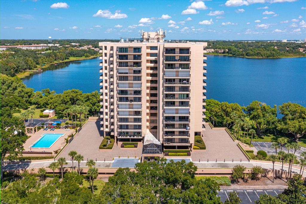An aerial view of a tall residential apartment building situated between two bodies of water — 7550 HINSON STREET UNIT 6A, ORLANDO, FL