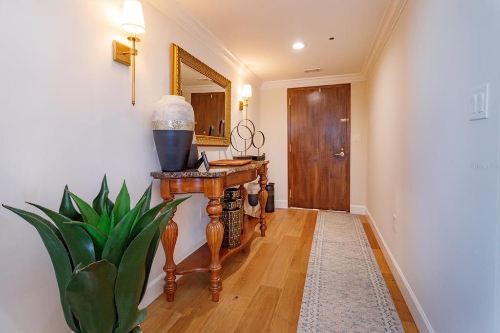 A hallway features a wooden console table, a mirror, wall sconces, and a runner rug — 7550 HINSON STREET UNIT 6A, ORLANDO, FL
