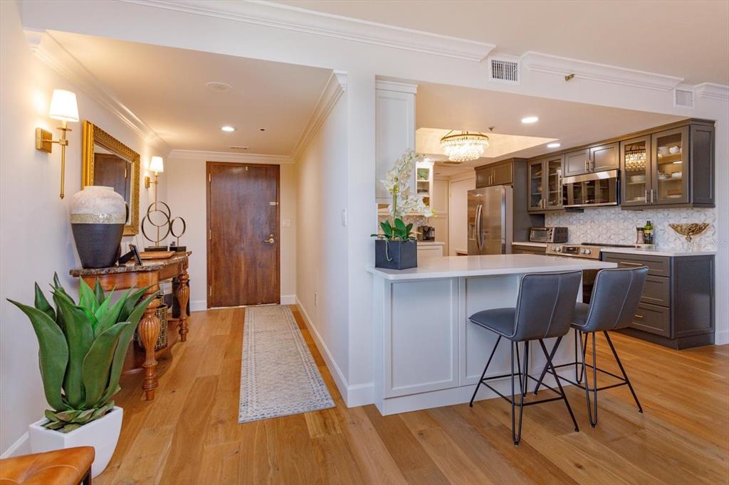 A kitchen with dark cabinets and a white island sits next to an entryway — 7550 HINSON STREET UNIT 6A, ORLANDO, FL