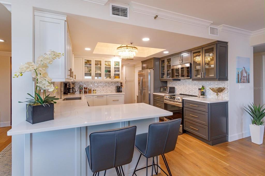 A kitchen features white and dark gray cabinetry, a quartz island, and wood flooring — 7550 HINSON STREET UNIT 6A, ORLANDO, FL