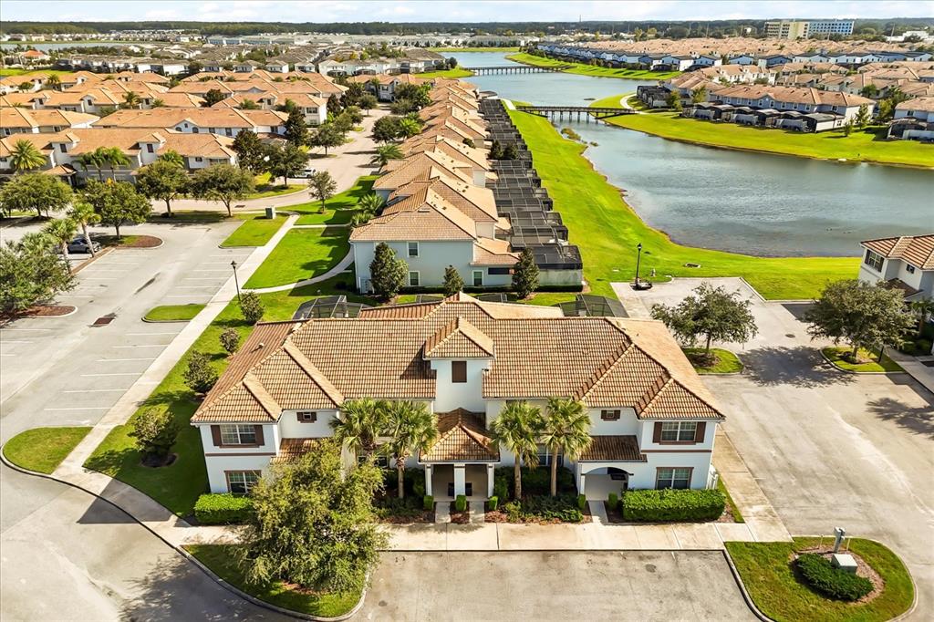 An aerial view shows a multi-unit residential building with a tiled roof near a lake — 4800 CRUSOE STREET, KISSIMMEE, FL