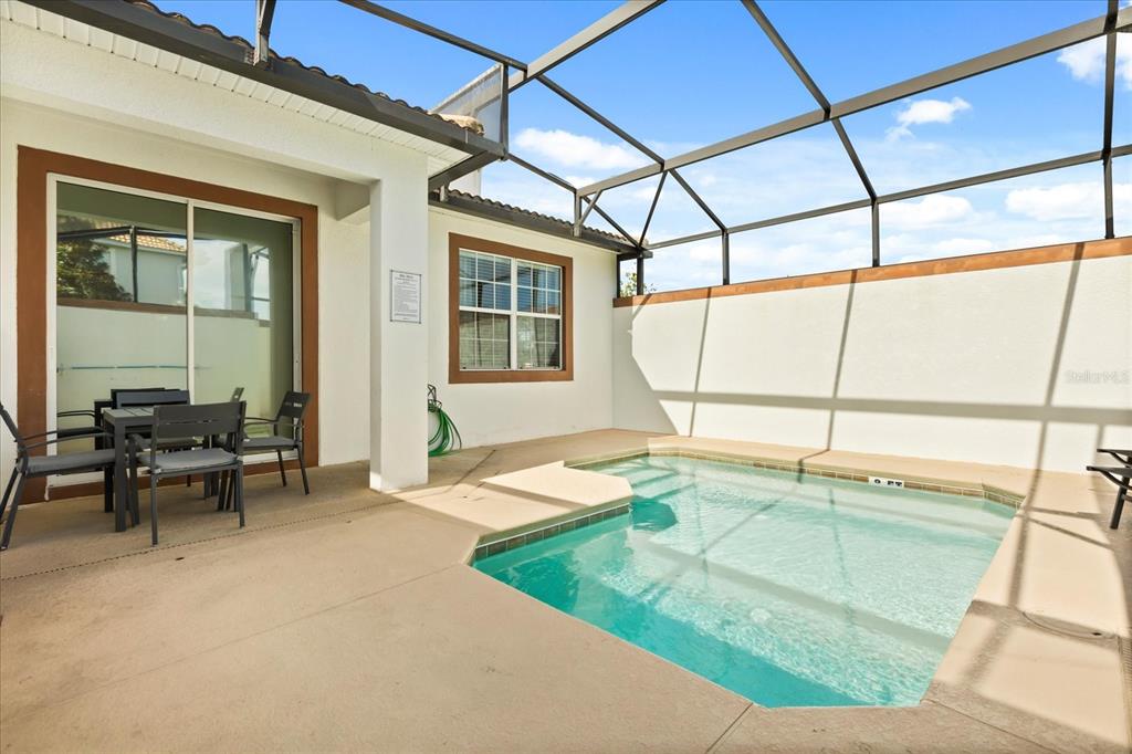 A screened-in patio features a small swimming pool and a dining set near sliding doors — 4800 CRUSOE STREET, KISSIMMEE, FL