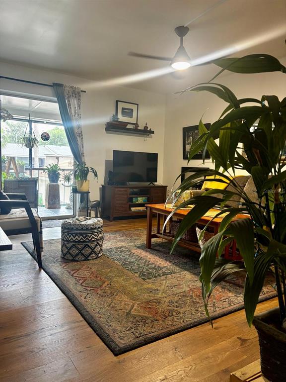 A living room features a patterned area rug, a television console, and a ceiling fan — 1180 PASEO DEL MAR UNIT C, CASSELBERRY, FL