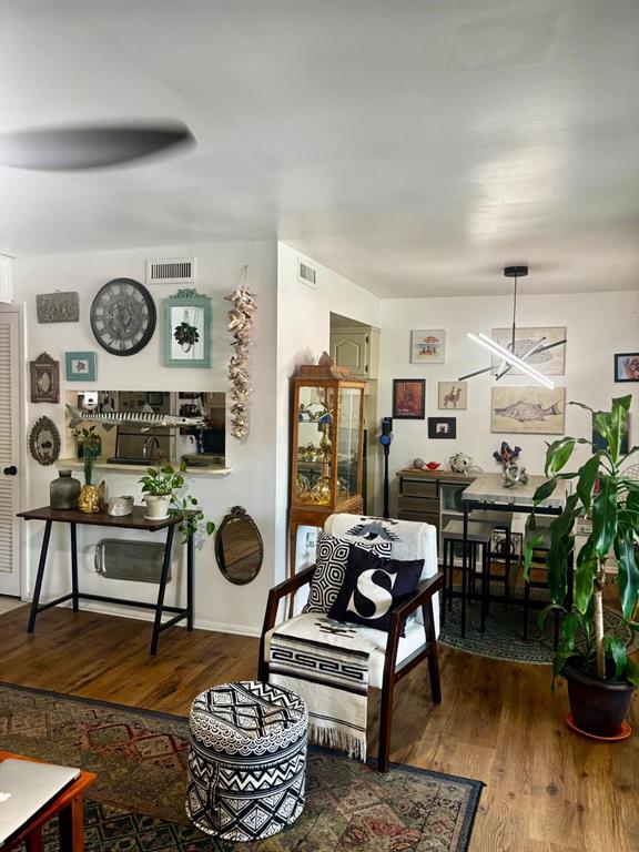 A living and dining area features wood flooring, a gallery wall, and a central armchair — 1180 PASEO DEL MAR UNIT C, CASSELBERRY, FL