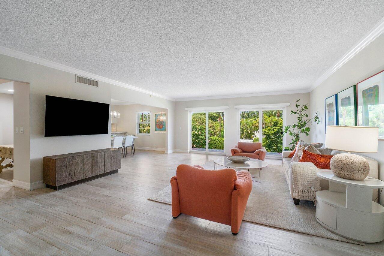 A living room features light wood-look tile floors, orange armchairs, a sofa, and sliding glass doors — 950 De Soto Road # 2b, Boca Raton FL 33432, BOCA RATON, FL