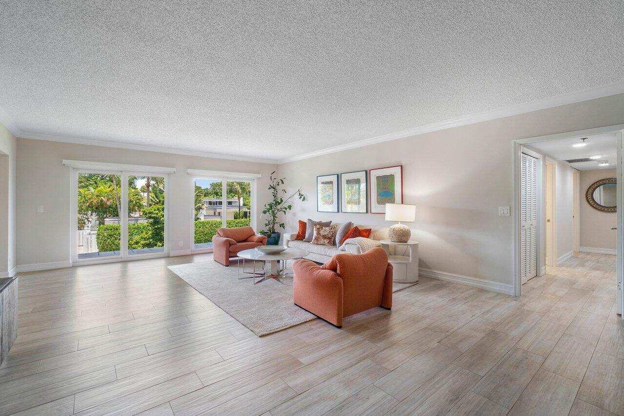 A living room features light wood-look tile floors, orange armchairs, a sofa, and sliding glass doors — 950 De Soto Road # 2b, Boca Raton FL 33432, BOCA RATON, FL