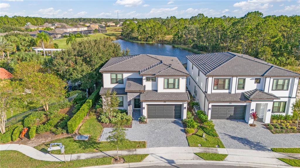 An aerial view shows two modern two-story houses with tiled roofs and paver driveways — 1205 BUTTERFLY ORCHID ROAD, DAVENPORT, FL