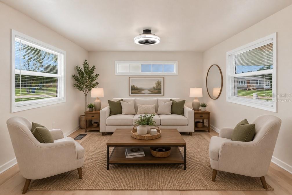 This virtually staged living room features a sofa, two armchairs, a coffee table, and windows — 16137 LAUDERDALE STREET, BROOKSVILLE, FL
