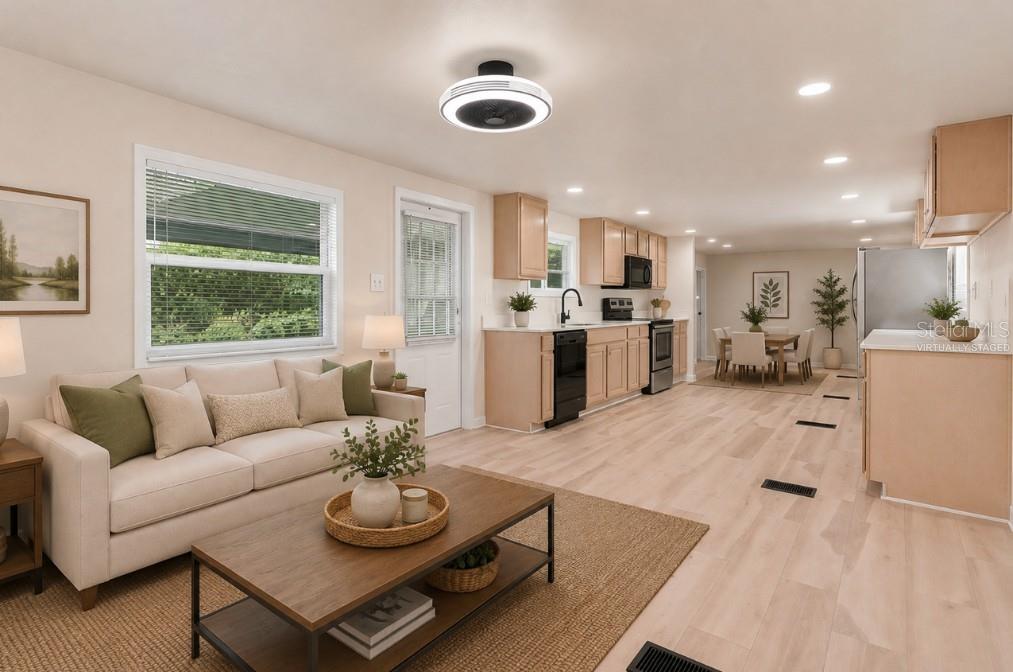 This virtually staged open-concept living room and kitchen features light wood flooring and neutral walls — 16137 LAUDERDALE STREET, BROOKSVILLE, FL
