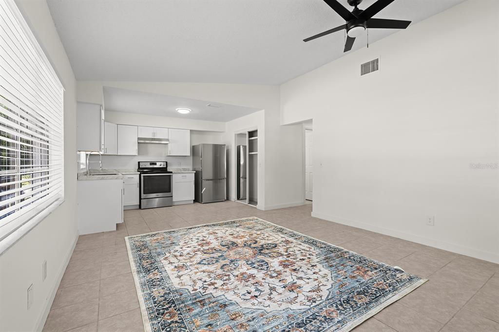 A kitchen with white cabinets and stainless steel appliances opens to a tiled living area — 452 N ELMWOOD POINT, CRYSTAL RIVER, FL