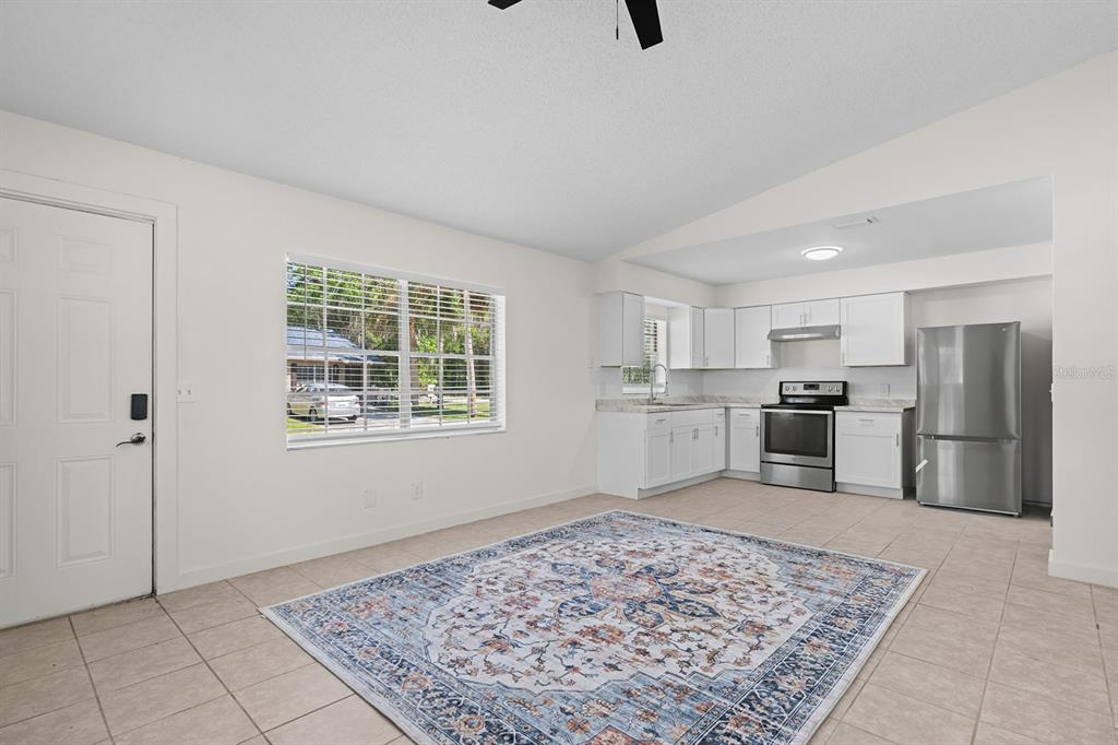 A bright, open-concept kitchen and living area features white cabinets, stainless appliances, and tile flooring — 452 N ELMWOOD POINT, CRYSTAL RIVER, FL