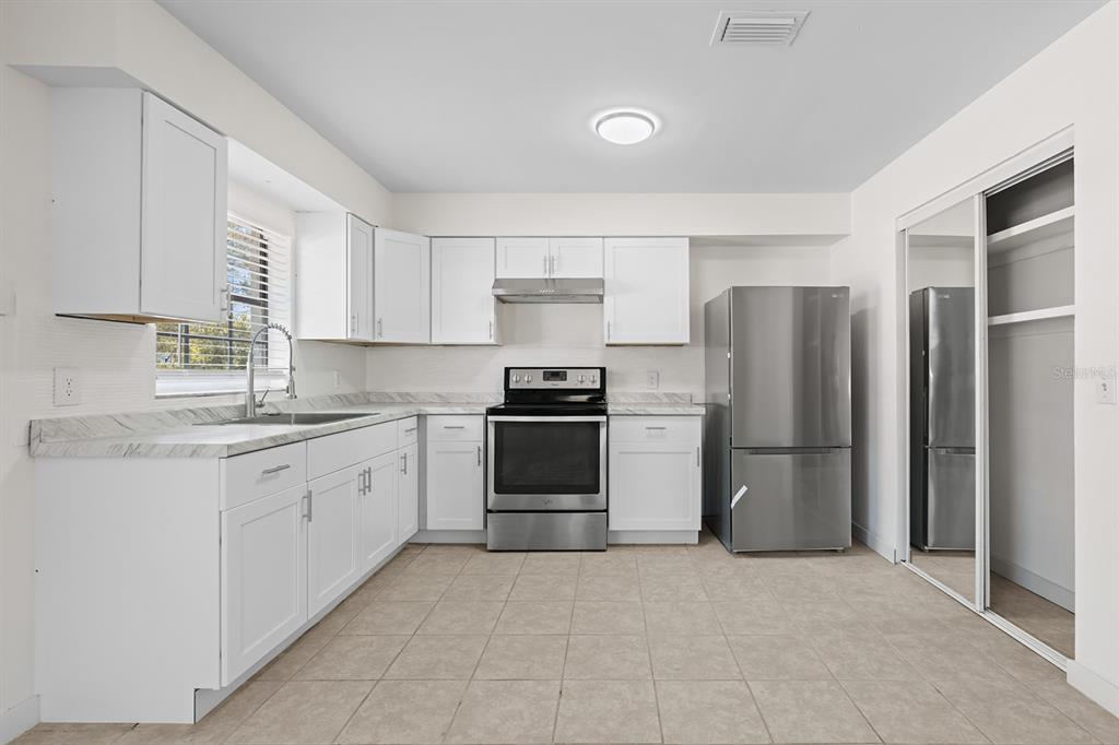 A kitchen features white cabinets, stainless steel appliances, marble-patterned countertops, and light-colored tile flooring — 452 N ELMWOOD POINT, CRYSTAL RIVER, FL