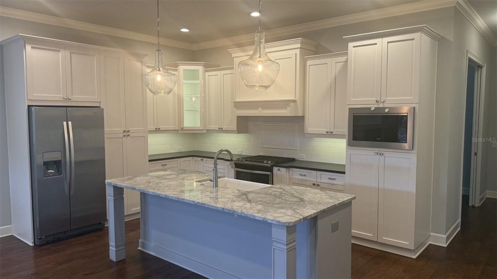A kitchen features white cabinetry, a marble-topped island, stainless steel appliances, and dark countertops — 636 SW 128TH TERRACE, NEWBERRY, FL