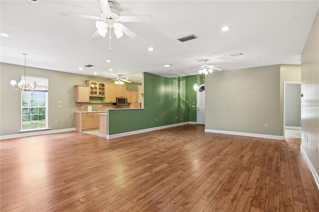 A spacious open-concept living area features wood-look flooring, a green accent wall, and a kitchen — 23378 LIVE OAK LANE, LIVE OAK, FL
