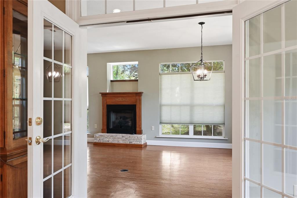 A view through French doors into a living room with hardwood floors and a fireplace — 23378 LIVE OAK LANE, LIVE OAK, FL