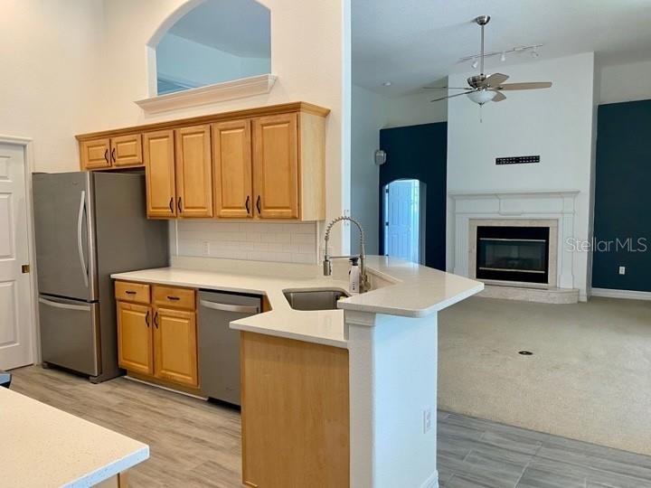 A kitchen with light wood cabinets and stainless steel appliances opens to a carpeted living area — 5224 HAMMOCK POINTE COURT, ST CLOUD, FL