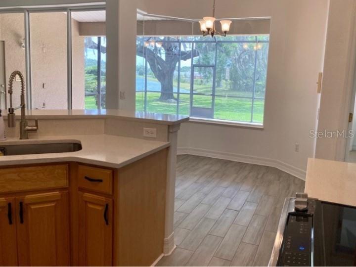 A kitchen with wood cabinets and a sink overlooks a dining area with large windows — 5224 HAMMOCK POINTE COURT, ST CLOUD, FL