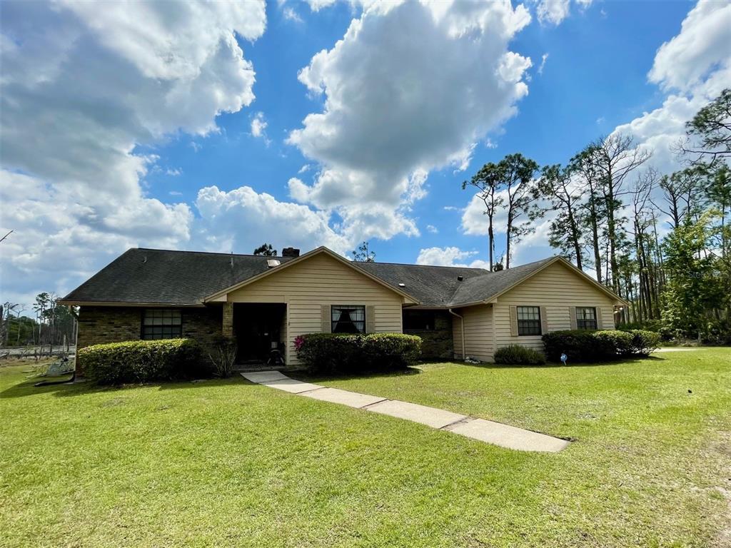 A single-story house with tan siding, a brick facade, and a concrete walkway — 349 SEMINOLE WOODS BLVD, GENEVA, FL