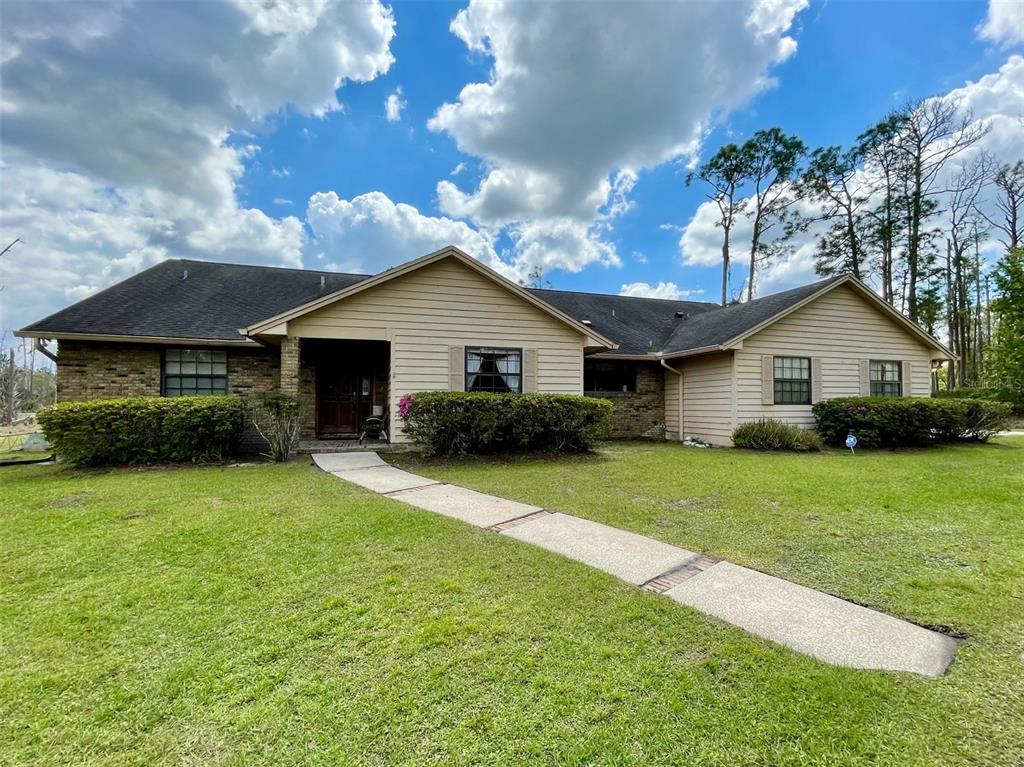 A one-story house with tan siding, brick accents, and a concrete walkway leading to the entrance — 349 SEMINOLE WOODS BLVD, GENEVA, FL