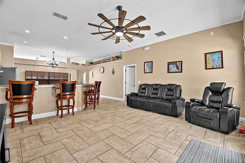 A living room with tile flooring, a black leather sofa, and a kitchen breakfast bar — 61 FRANCIS LN, PALM COAST, FL