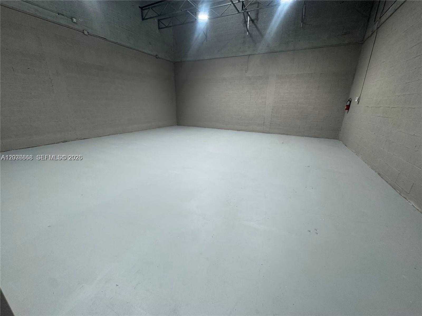 An empty industrial warehouse space features gray concrete block walls and a painted concrete floor — 10171 NW 58th St # 11, Doral FL 33178, DORAL, FL