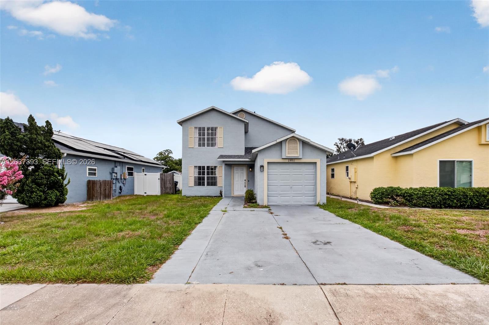 A two-story light blue house with a single-car garage and a concrete driveway — 1951 TROPIC BAY CT, Orlando FL 32807, ORLANDO, FL