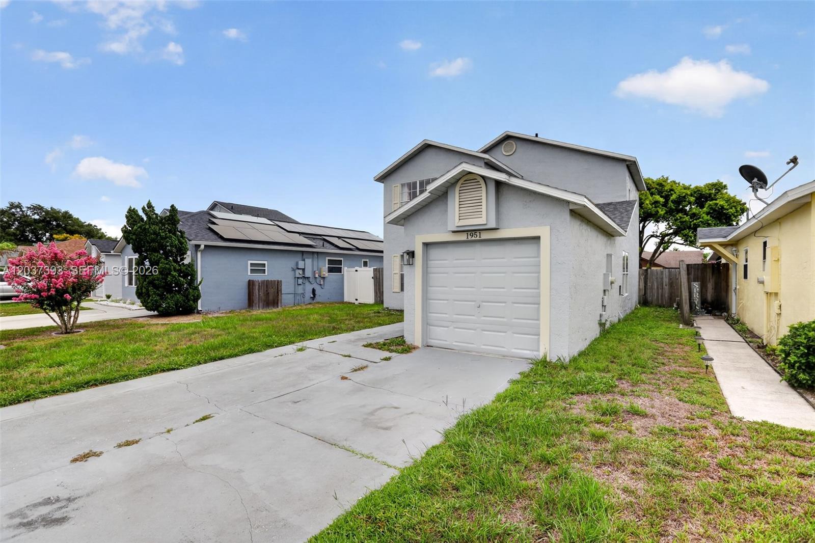 A gray two-story house features a front-facing garage and a concrete driveway — 1951 TROPIC BAY CT, Orlando FL 32807, ORLANDO, FL