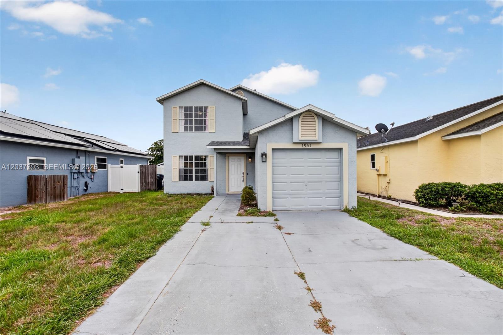 A two-story light blue house features a single-car garage and a concrete driveway — 1951 TROPIC BAY CT, Orlando FL 32807, ORLANDO, FL